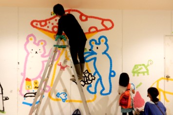 カラーテープで親子で壁に絵を描いている様子