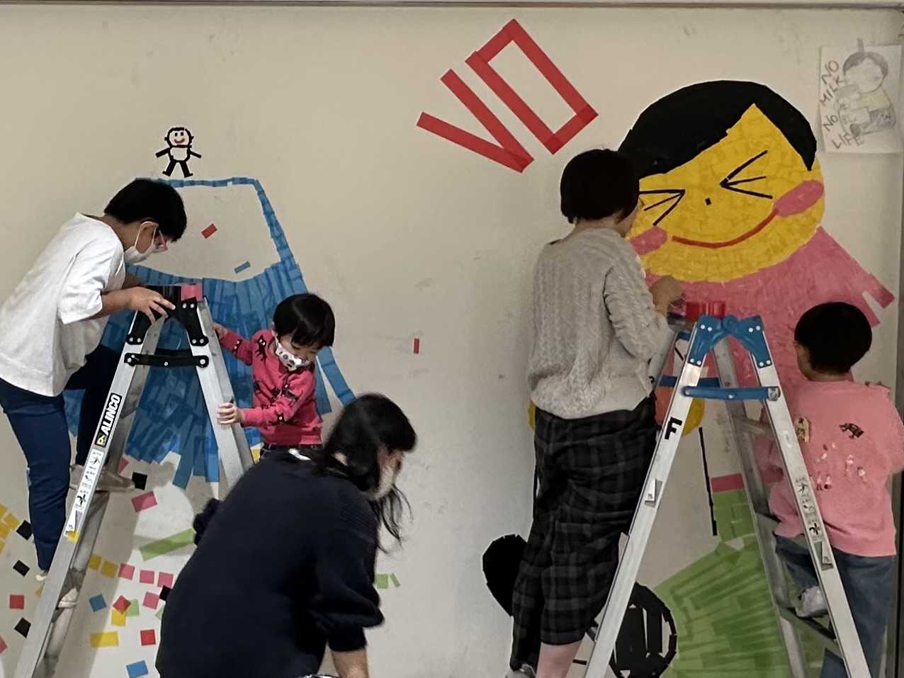 カラーテープを壁に貼る親子