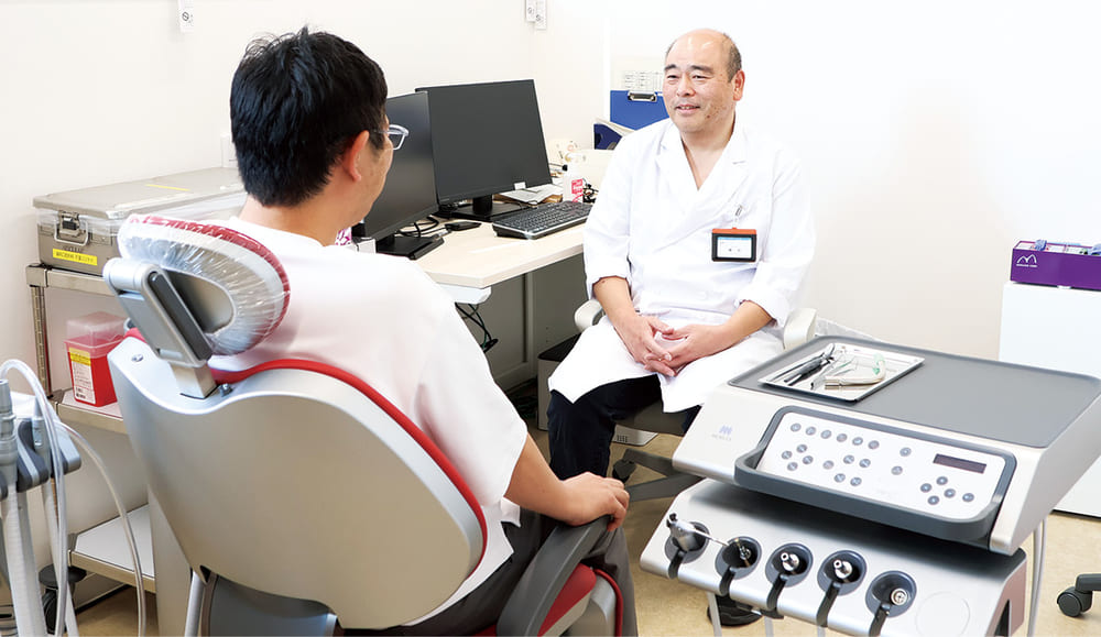 診療室で患者と向き合って診療する歯科口腔外科の医師