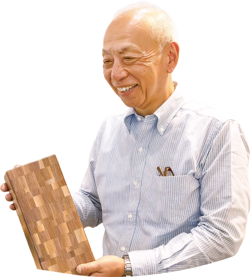 寄木の文様が入った板を手に持ってほほ笑む露木さん
