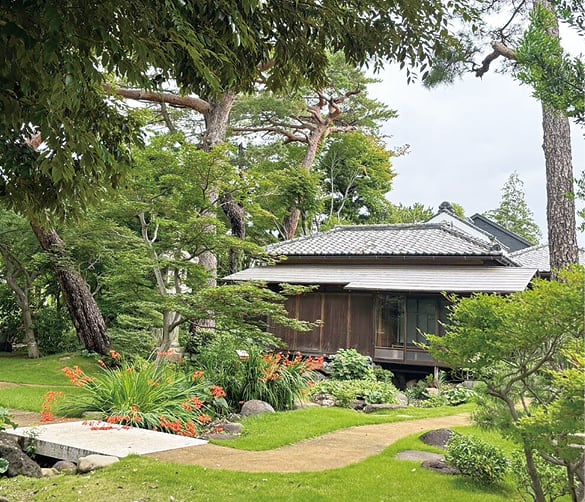 池と樹木を配した回遊式庭園越しに旧松本剛吉別邸の主屋を望む