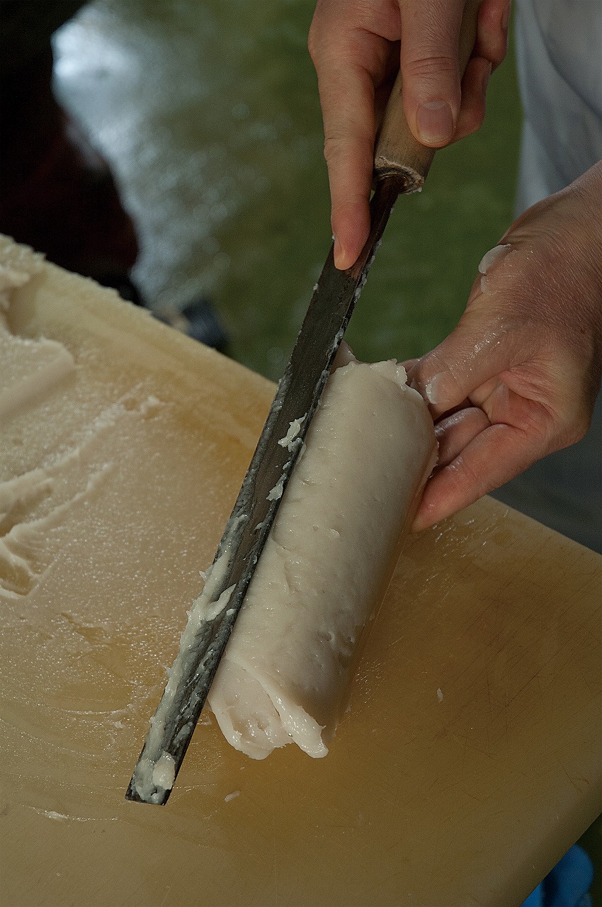 職人の手によって、付包丁一つで裏ごしされたすり身を蒲鉾板に厚く扇形に盛リ付ける様子