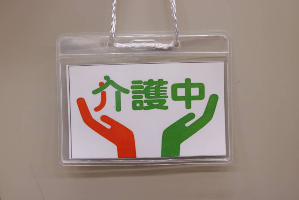 介護中を示す「介護マーク」。オレンジと緑のカラーで、支えあうようすがデザインされている。