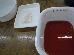 （左から）媒染剤、染色前の絹のスカーフ、ビワの液