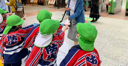 幼年消防クラブの子どもが小田原駅の駅頭にて広報活動している様子