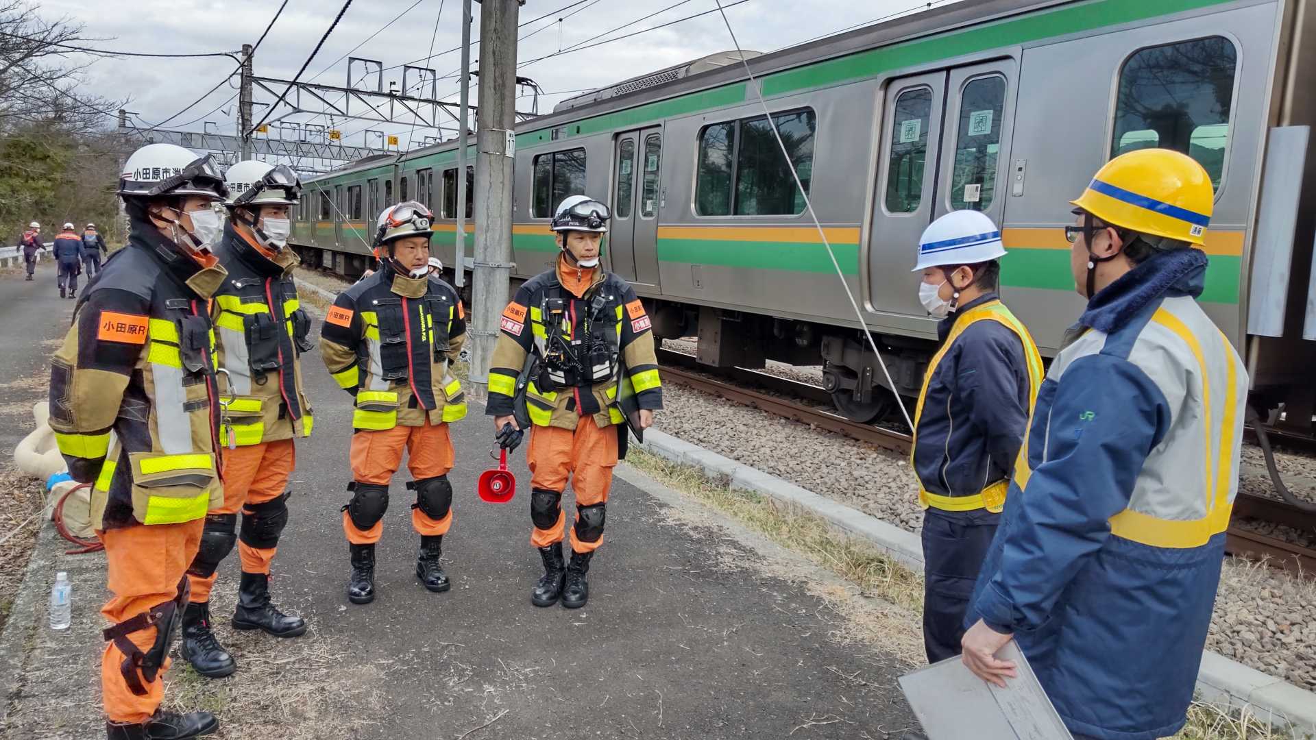 救助隊員がJR職員から列車を持ち上げる際の注意事項を受けている写真。