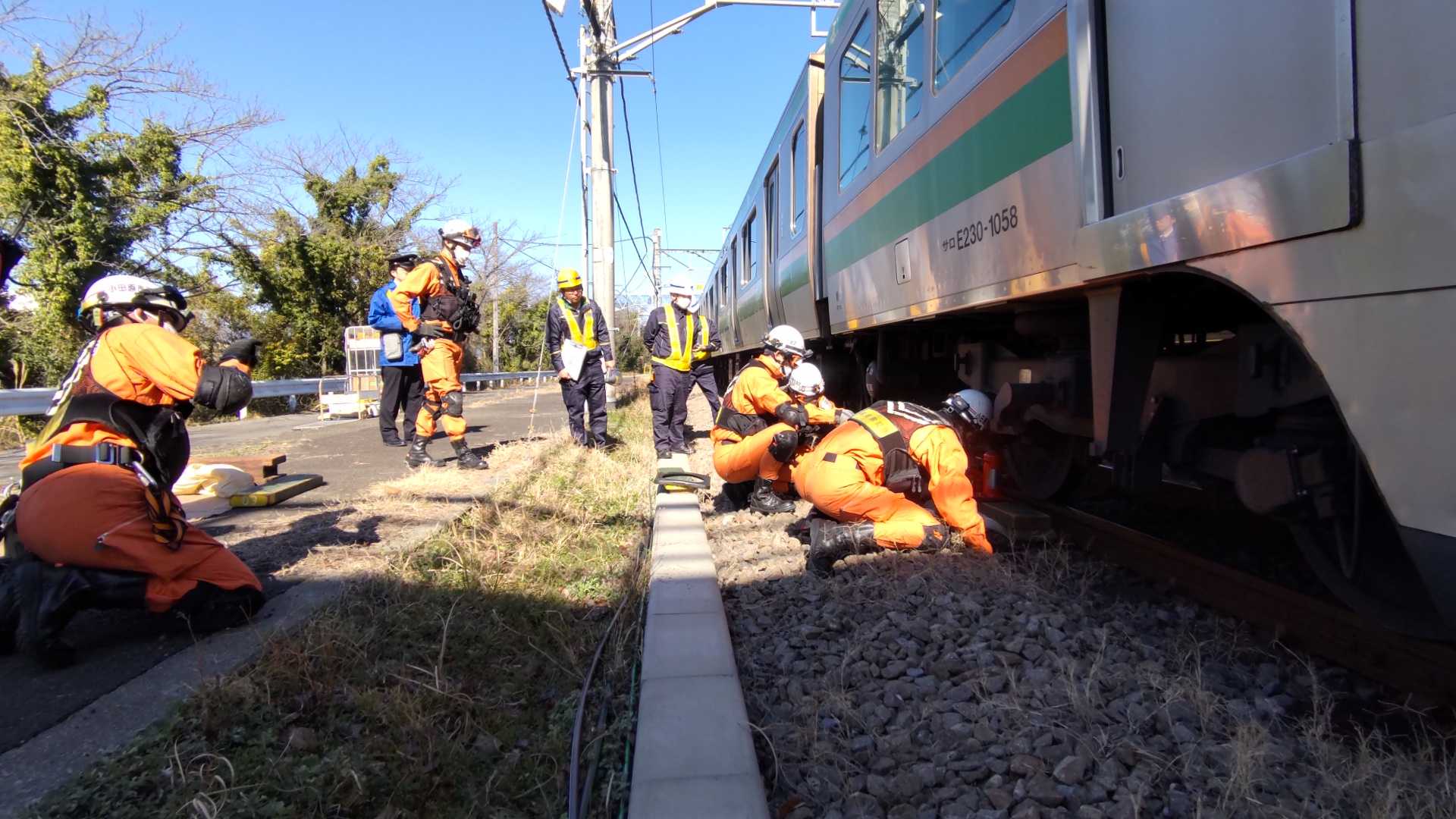 列車の下敷きになった要救助者を救出するため、JR職員の助言を得ながら、ジャッキアップポイント等を確認している写真。