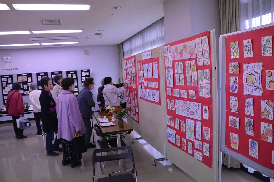 第一講習室絵：イベントを訪れた人達が絵手紙の展示を見ている様子　
