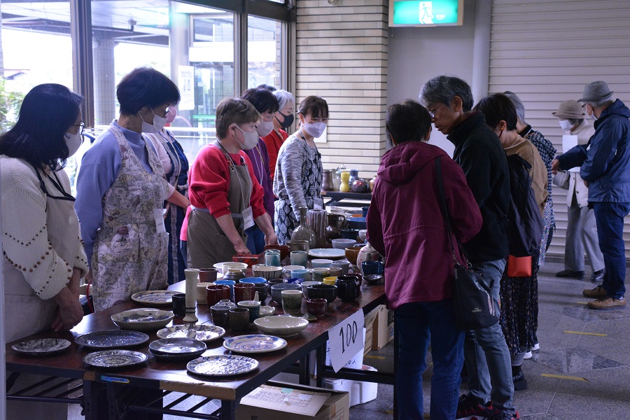 陶芸チャリティー　様々な自作の陶芸作品を販売している、売り子とお客が会話をしている。