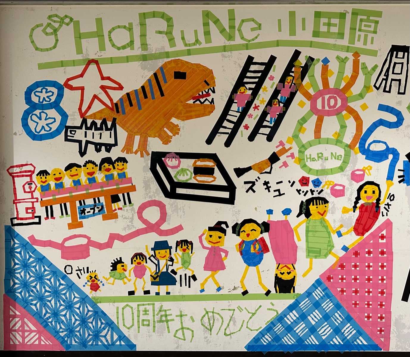 ハルネ小田原の白い壁に子どもたちが色とりどりのテープを張り付けて、作成したアート。