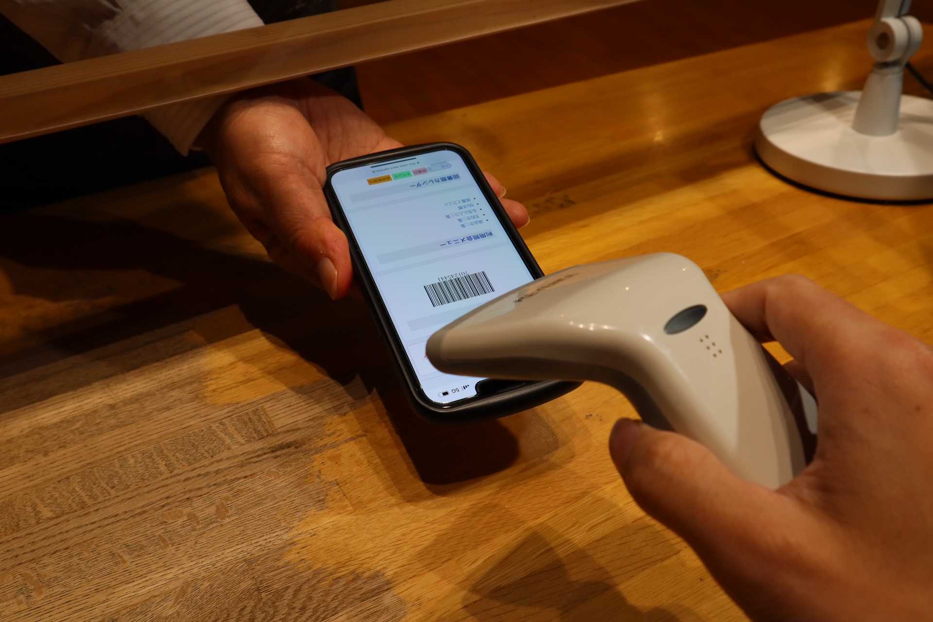 スマホに表示したバーコードで本の貸し出し手続きをしている様子