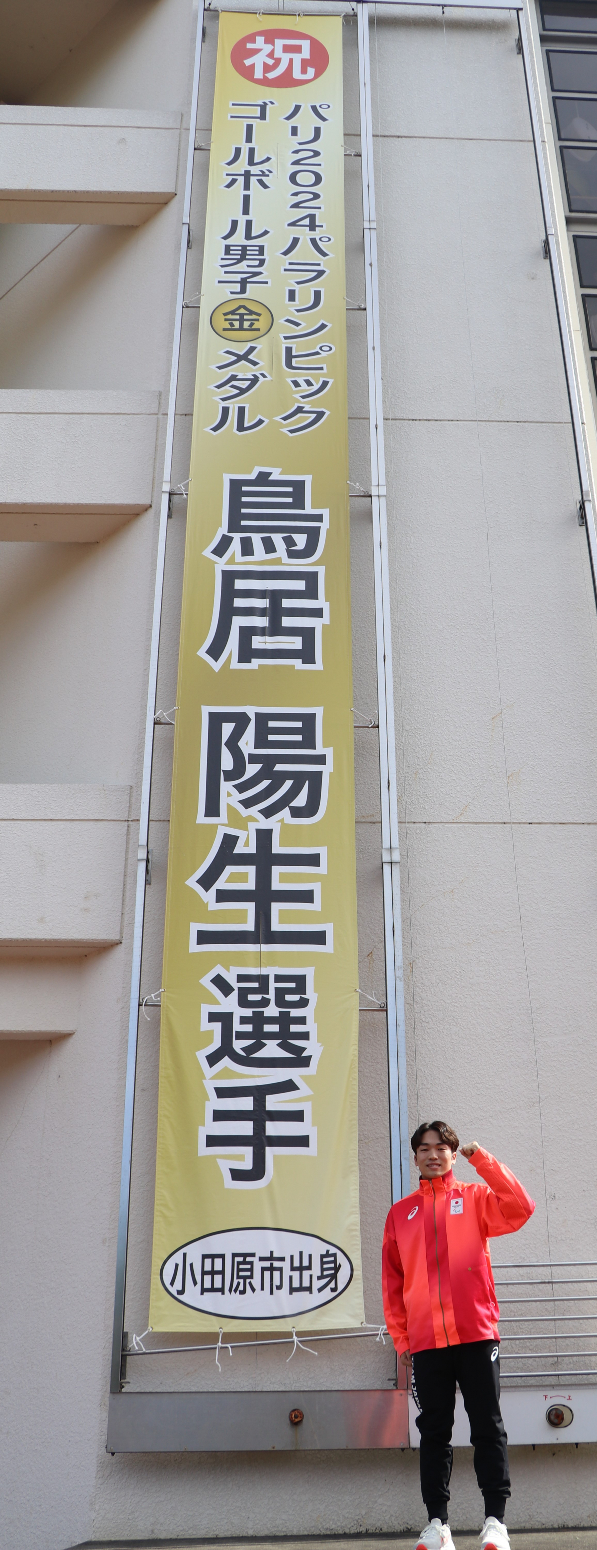 金メダル獲得を祝う懸垂幕の前で