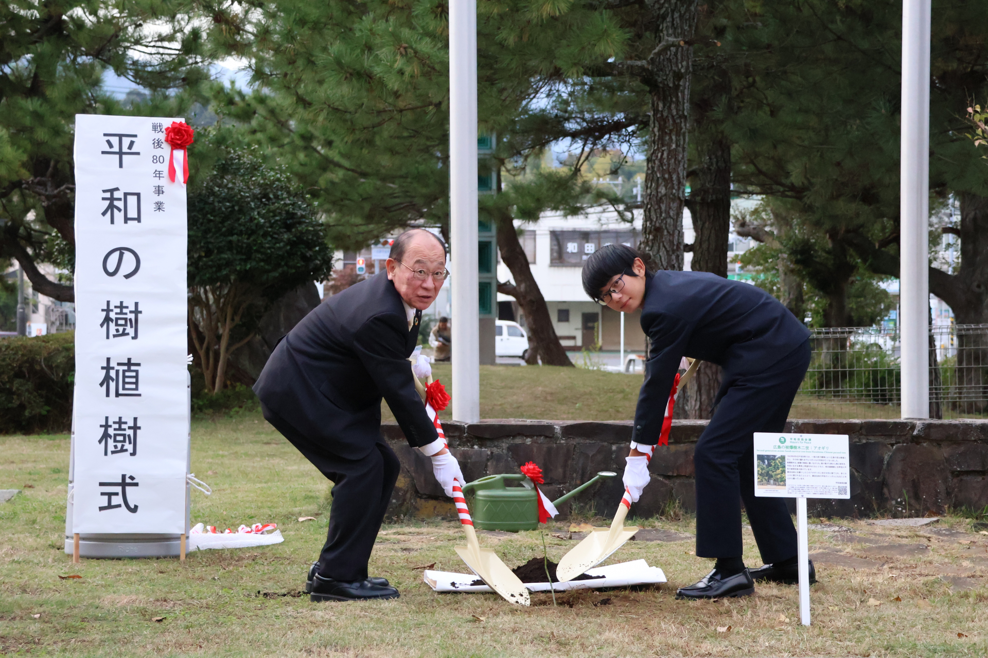 柳下教育長と代表生徒の土かけの様子