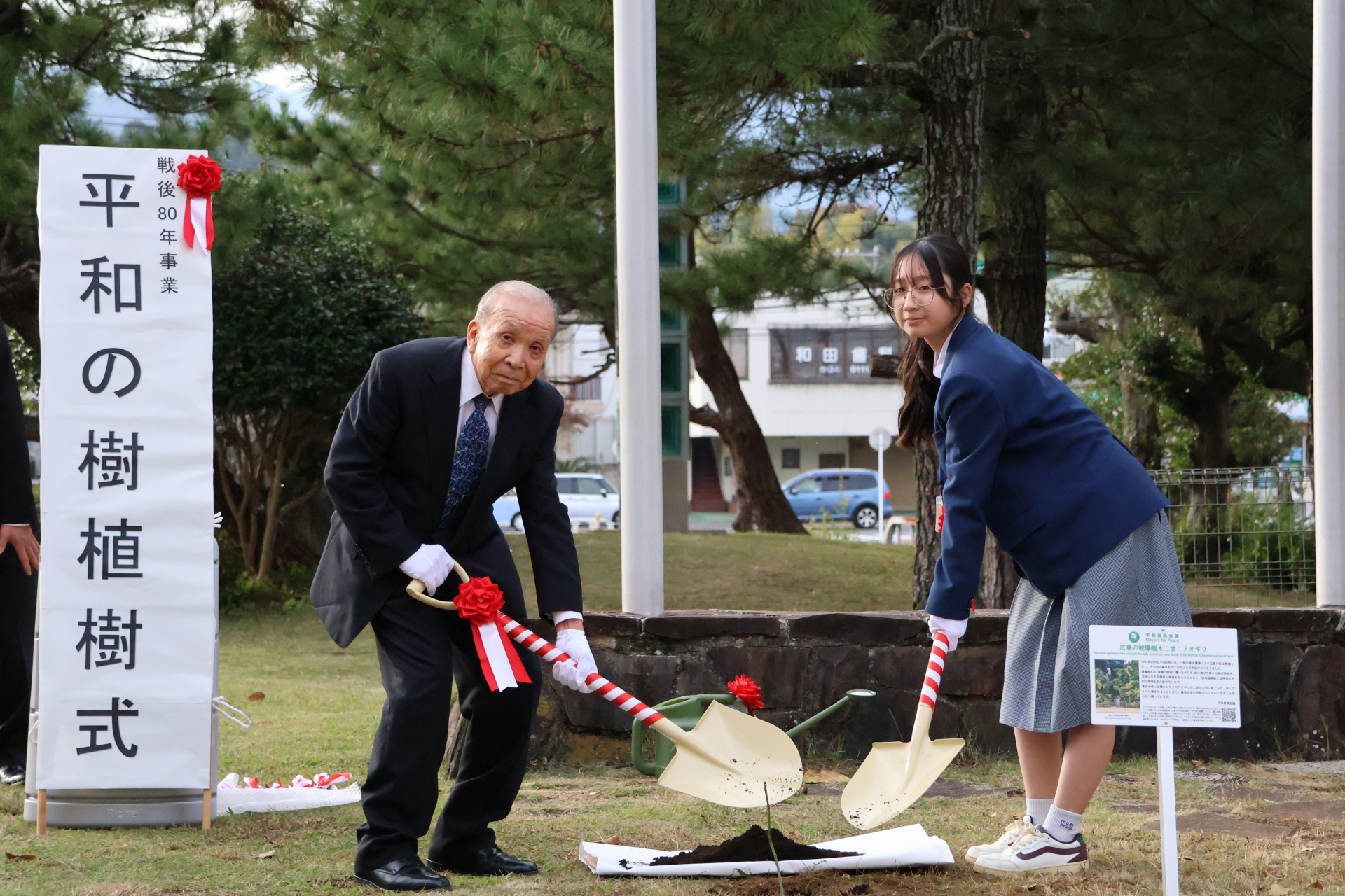 石綿遺族会会長と代表生徒の土かけの様子