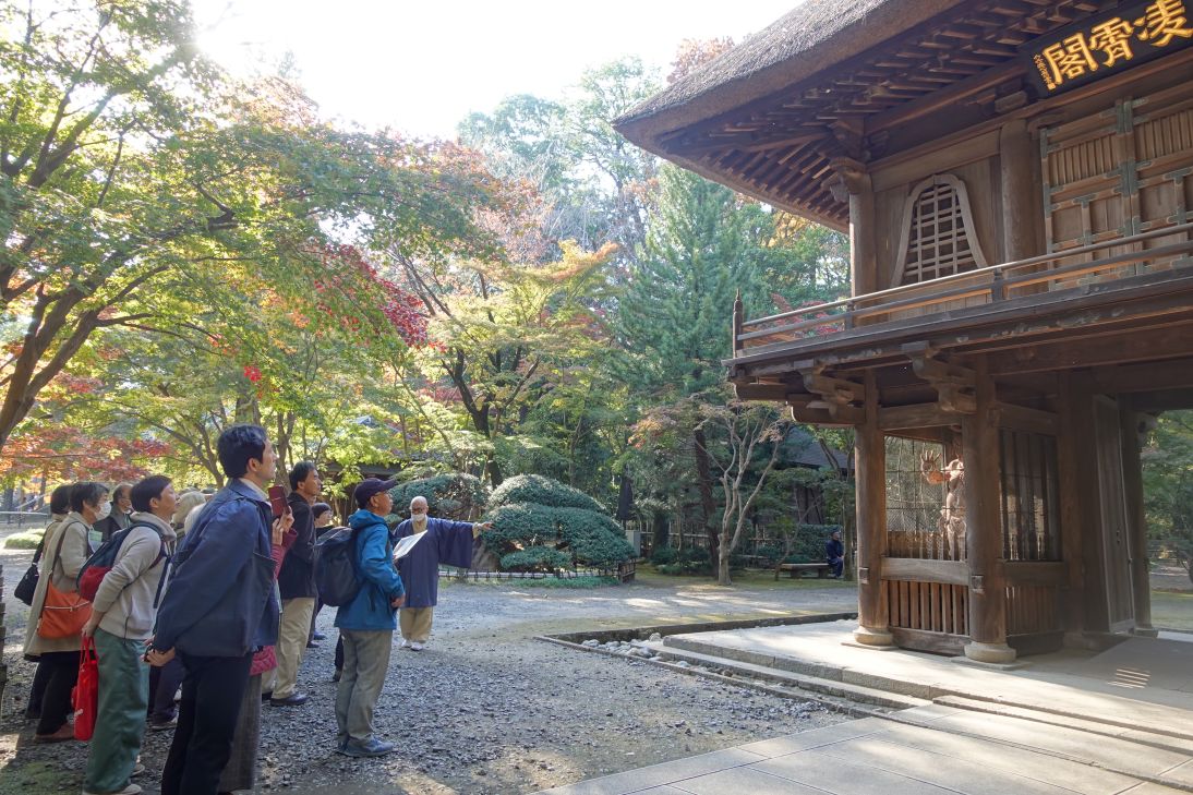 平林寺山門にて住職から松永安左ヱ門寄贈の仁王像の説明を受ける様子