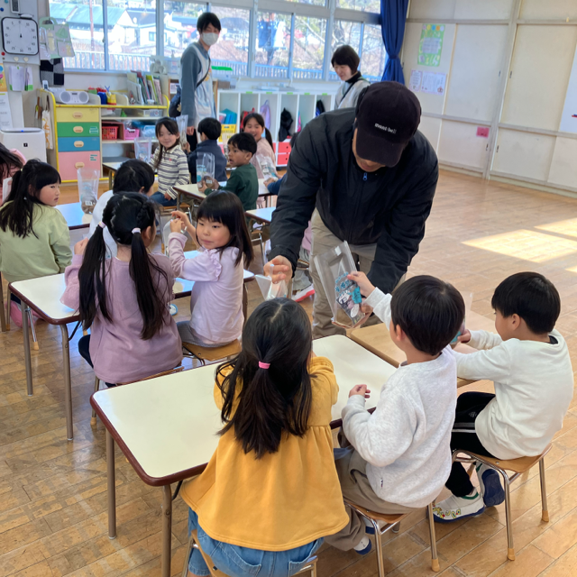 キウイ農家が子供にキウイを手渡している様子