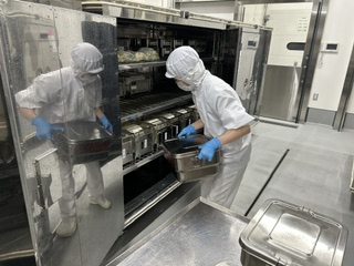 学校のコンテナに食缶や食器を入れます